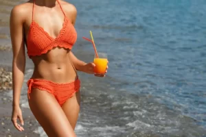 Jak nowatorskie technologie pomagają osiągnąć smukłą sylwetkę na lato bez wyrzeczeń? 3 woman on the beach with a glass of cocktail 2024 10 16 20 25 56 utc